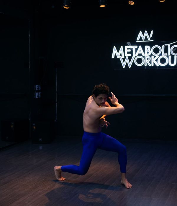 Man performing a controlled strength exercise in a dark studio.